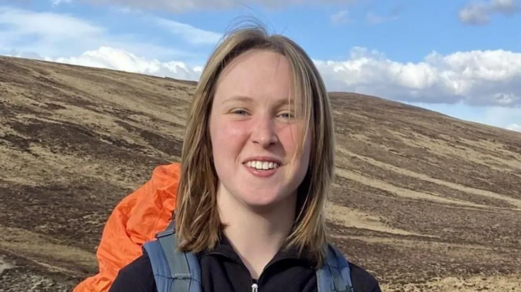 A head and shoulders photo of Georgia Scarff. She is smiling and seems happy. She appears to be on a trek on a mountain.