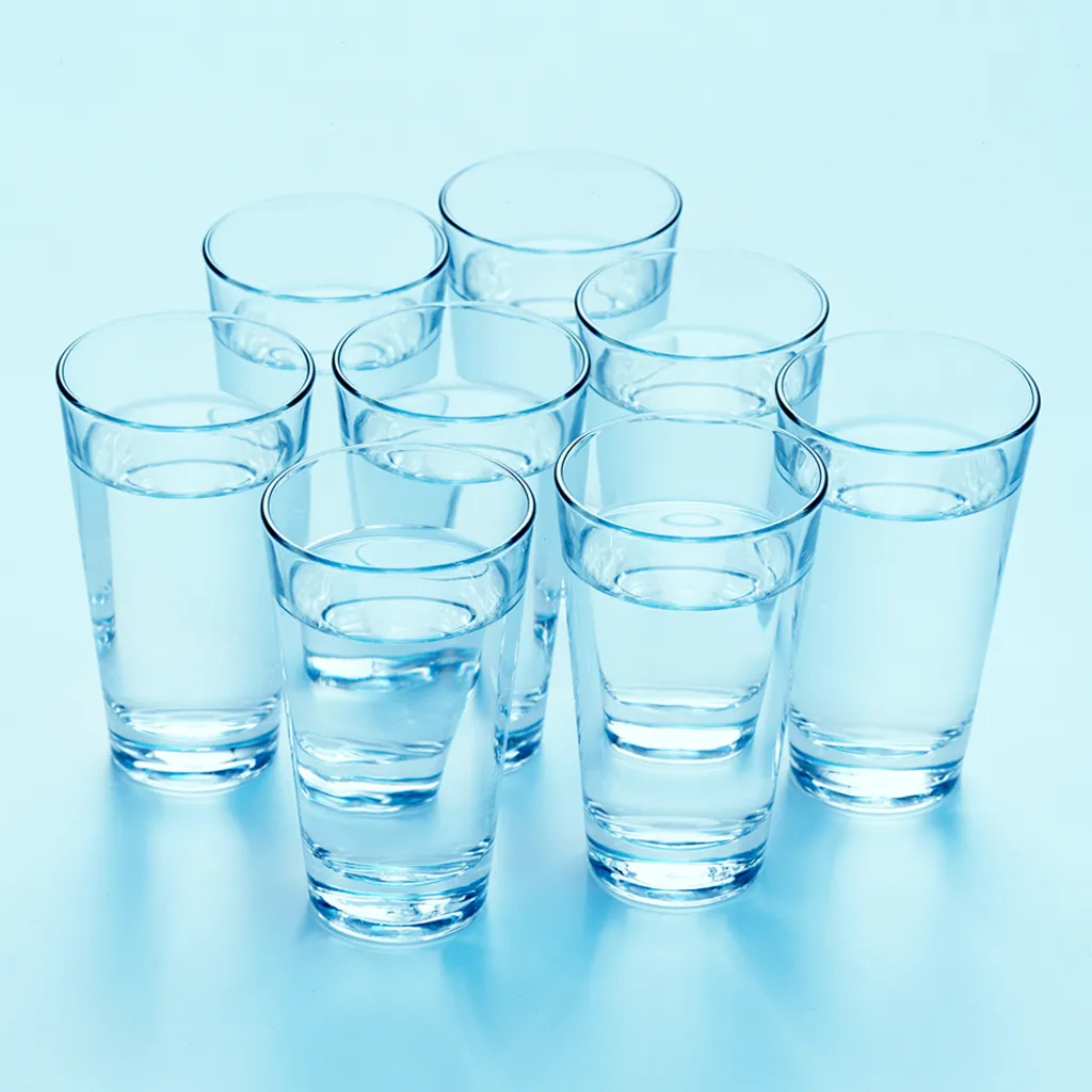 Eight clear glasses filled with water, arranged in a triangular formation on a light blue background. Each glass is evenly spaced.