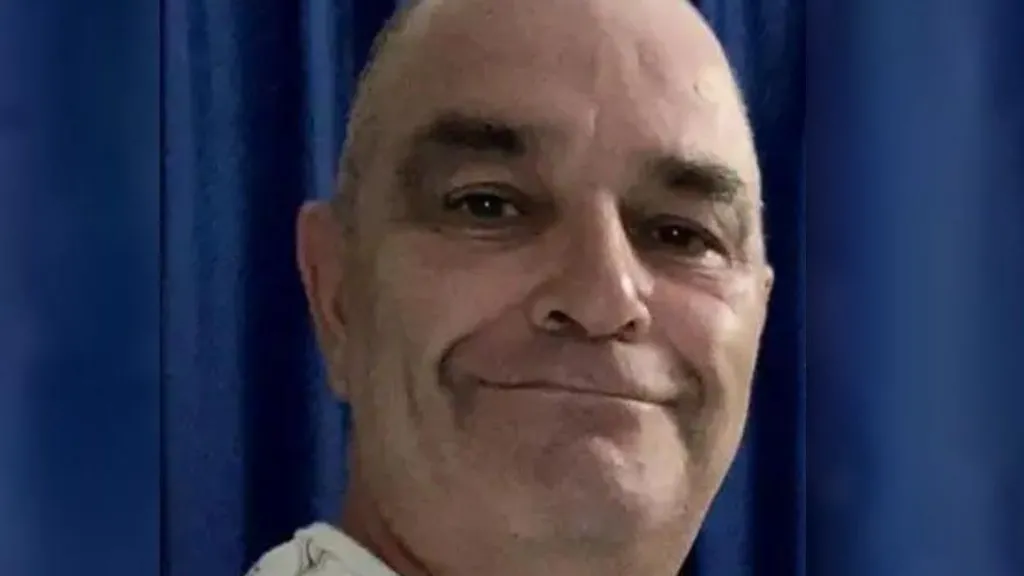 Keith Rollinson, who has a bald head, is smiling at the camera