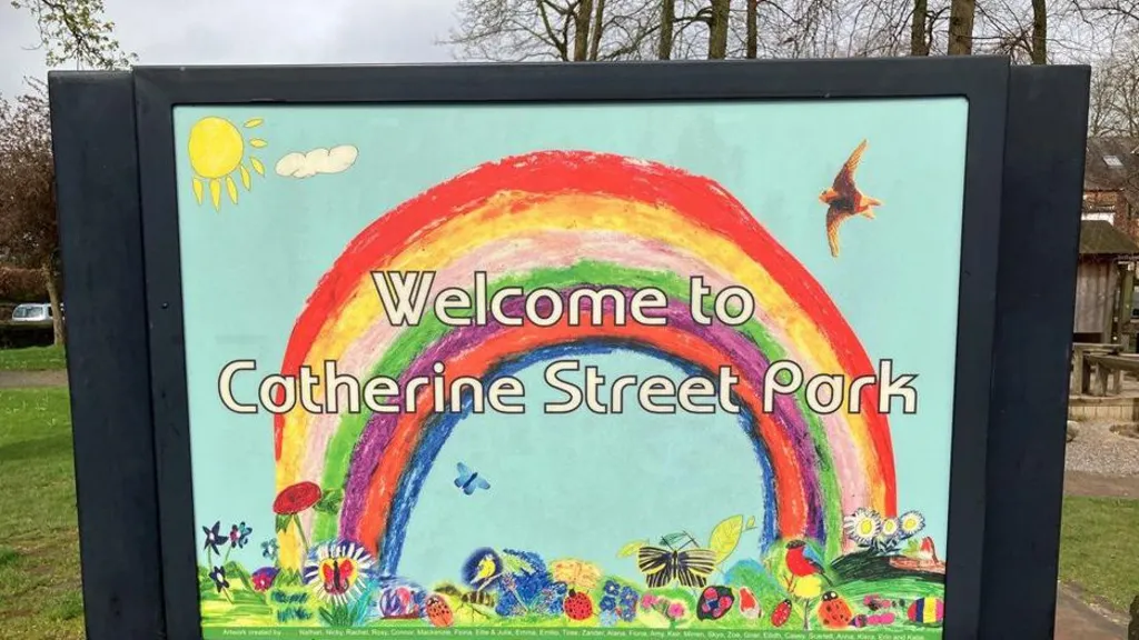 A sign welcoming people to the Catherine Street Park featuring a rainbow, yellow sun, birds, flowers and lots of wildlife like butterflies and ladybirds.