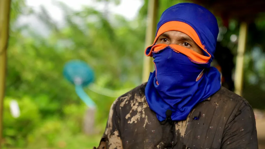 Javier, a local farmer wearing a blue balaclava. the photo is taken during an interview and shows hie head and shoulders, but only his eyes are visible. 