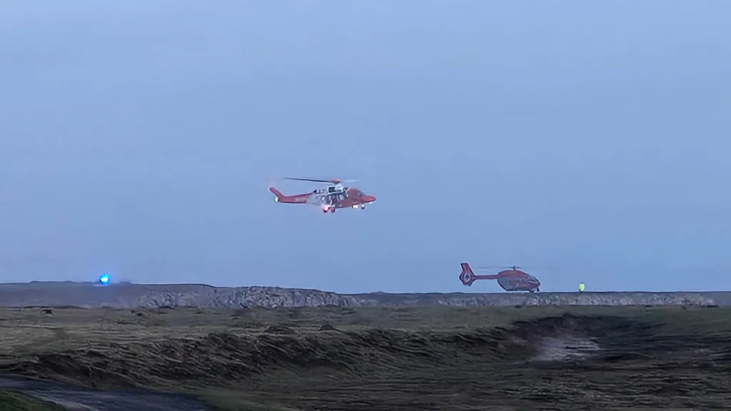 Two helicopters around a coastline