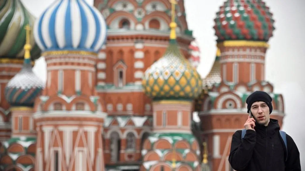 Man in black talking on the phone in Russia's Red Square with Saint Basil's Cathedral in the background