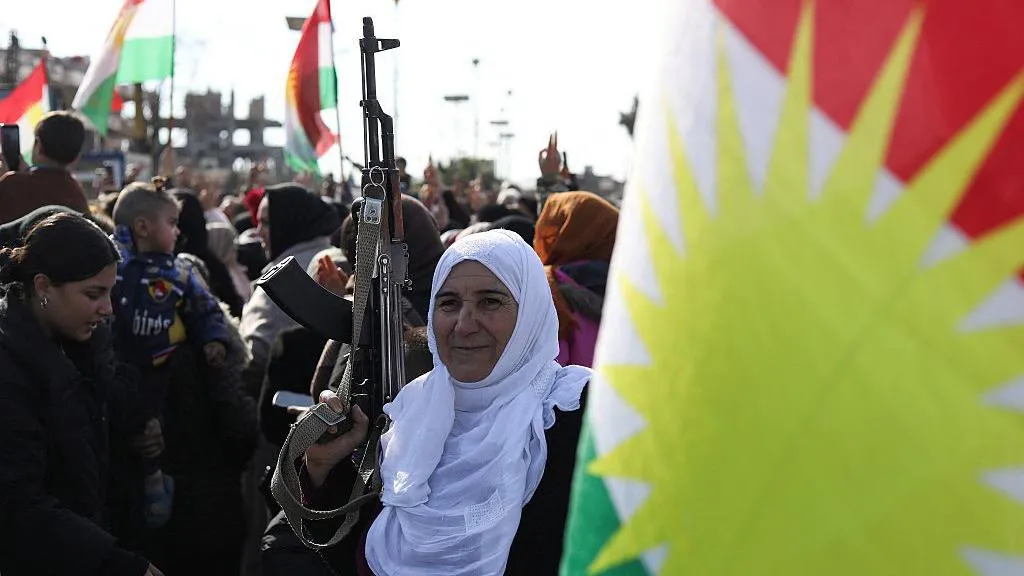 A woman holds a rifle at a protest by Kurds against a government offensive in north-eastern Syria, in Qamishli, Syria (20 January 2026 
