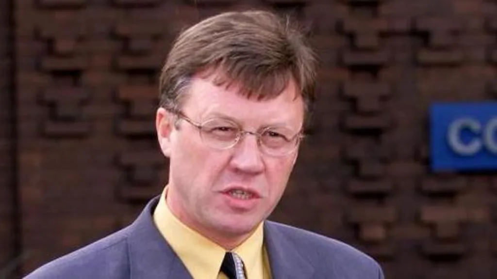 Det Supt Roy Lambert standing outside Suffolk Police headquarters in Martlesham in 2002. He has short brown hair and wears glasses, a blue suit and yellow shirt and black tie. 