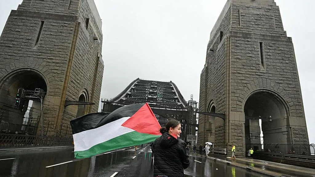 A protester with the Palestinian flag marches on the Sydney Harbour Bridge