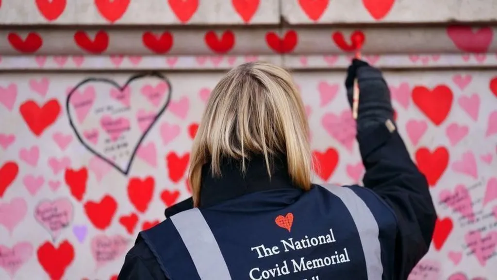 A volunteer repaints a heart on the Covid memorial wall in London