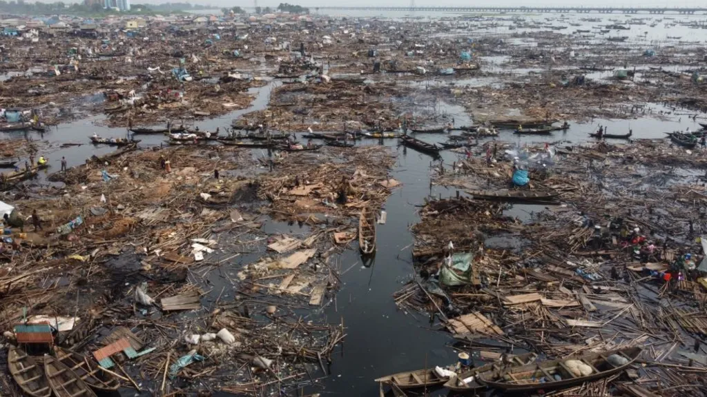 Wooden debris and boats in Lagos Lagoon with Third Mainland Bridge in the distance.