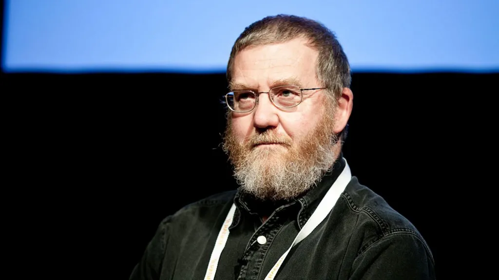 Bearded, Professor Mark Whitehorn, wears a black denim shirt.