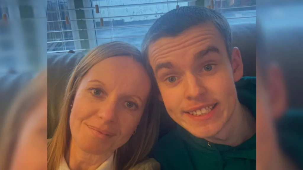 Alma has long blonde hair and blue eyes as she sits next to Caleb on the sofa. Caleb has short dark hair and blue eyes.