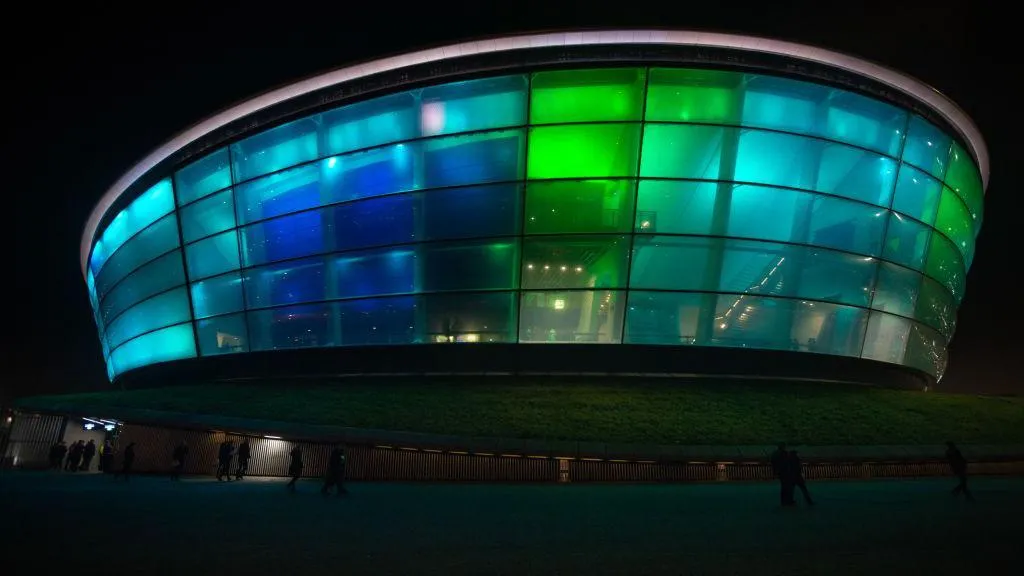 The OVO Hydro concert venue lit up in greens and blues on a dark night