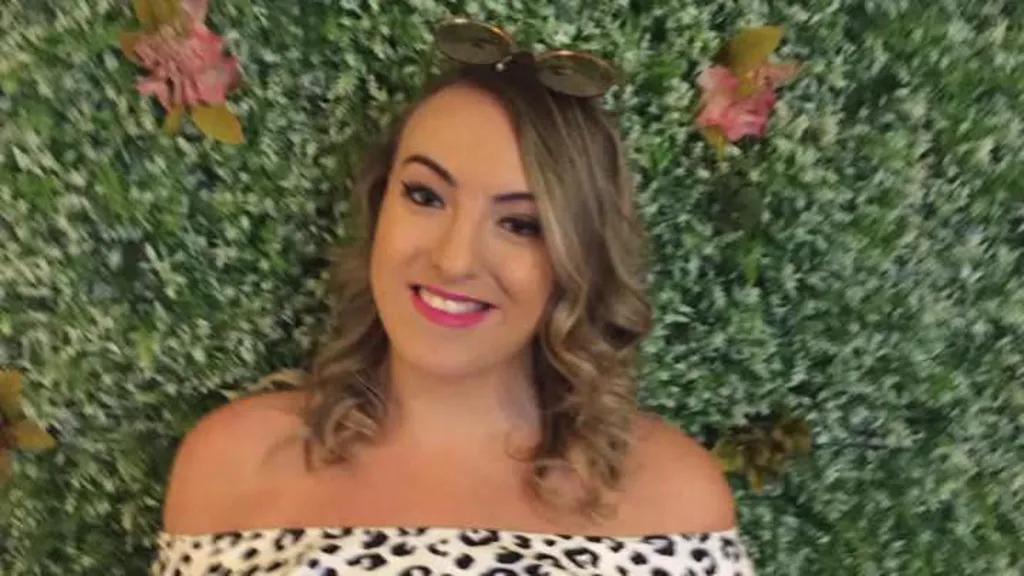 a young woman with curly brown hair smiling