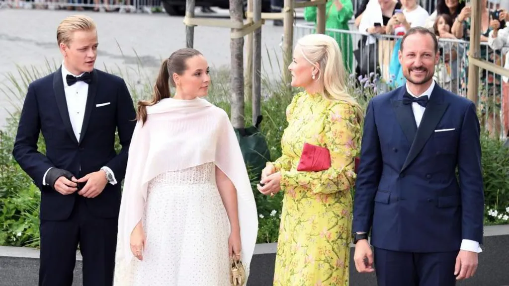 Four people in smart clothes with men in bow ties on the outside and two women in white and yellow in the centre