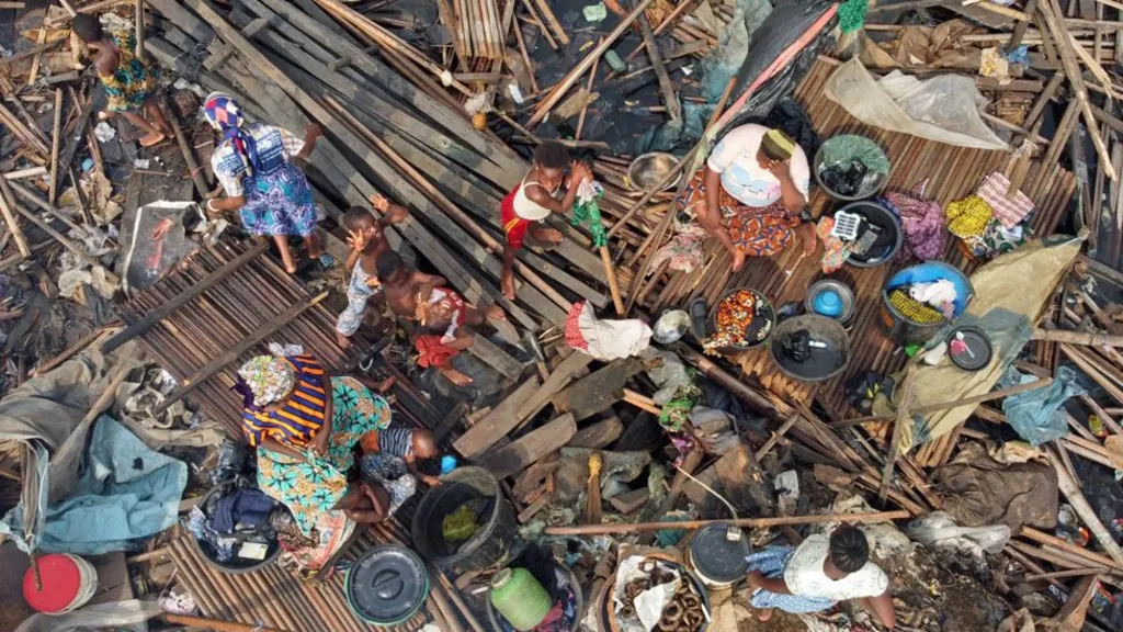 A birds-eye view of women and children sitting on wooden debris in Makako slum.