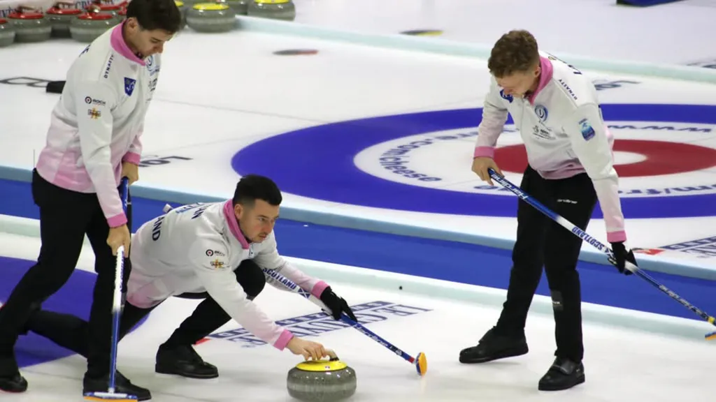 Team Mouat players Grant Hardie, Hammy McMillan and Bobby Lammie in action in Finland, as Hammy prepares to throw the curling stone and Grant and Bobby stand either side preparing to sweep