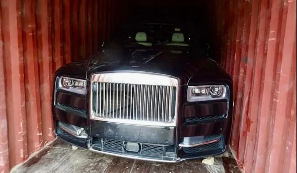 A black luxury vehicle inside a red shipping container