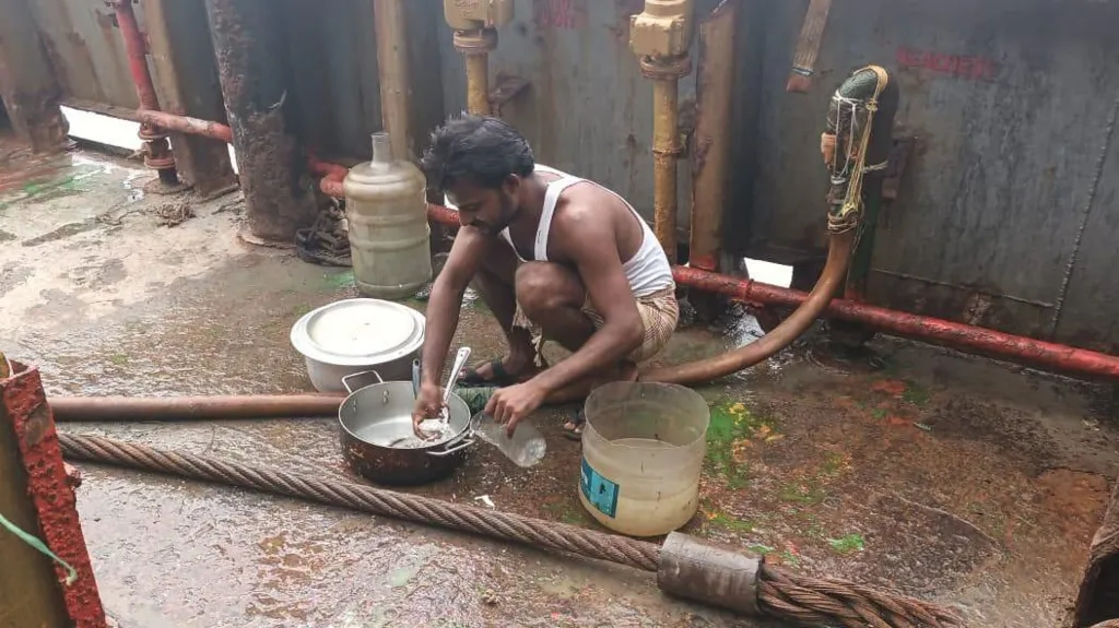 A sailor on an abandoned ship pours fresh water from a tank