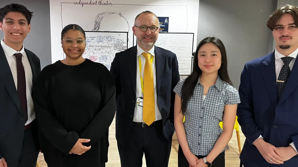 Jai, Anya, Alex Crossman, Kami and Ismael stand in a line and smile at the camera.

