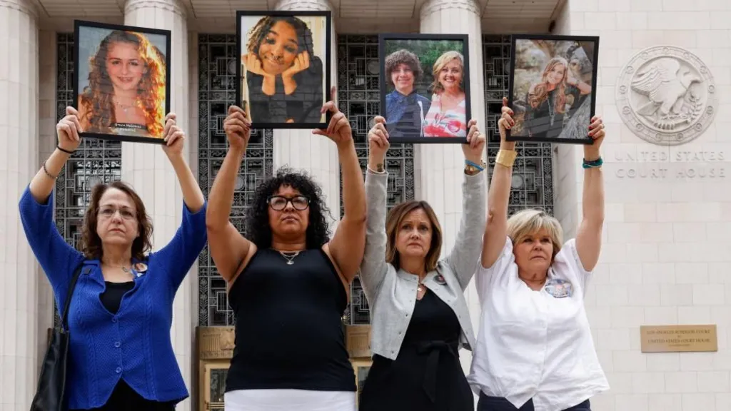 Four parents holding up framed photos of their children, whom they say died due to social media–related harms standing alongside one another outside a courthouse in Los Angeles.