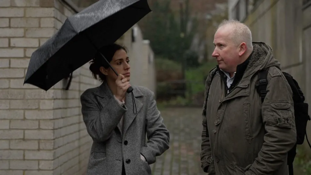 Meghan Owen holds an umbrella and is talking to Pete Elliott in the estate
