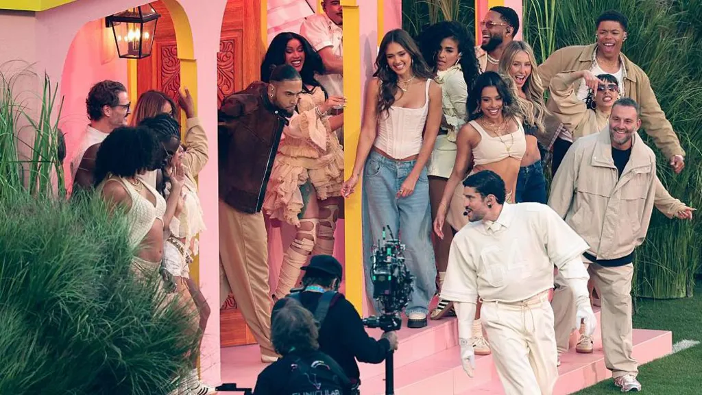 Celebrities gathered on the porch of Bad Bunny's pink Casita, while Bad Bunny, in cream, dances. 
