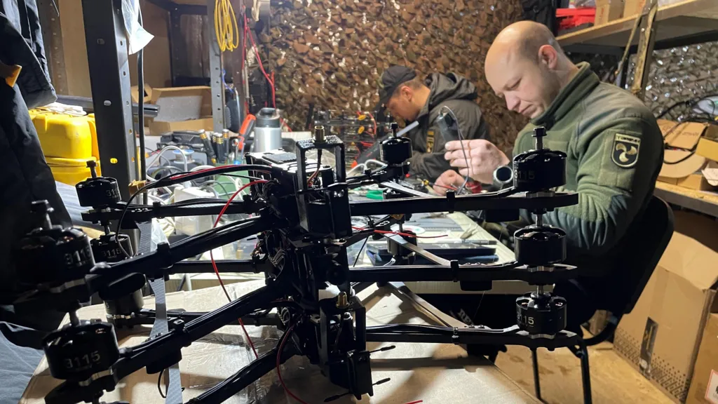 Uniformed Ukrainians in a workshop repair drones for use on the battlefield