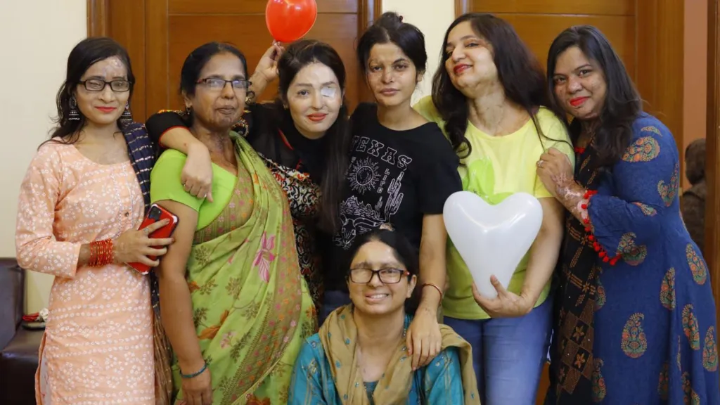 Acid attack survivors, many of them have scars on their faces, stand around Shaheen Malik. 