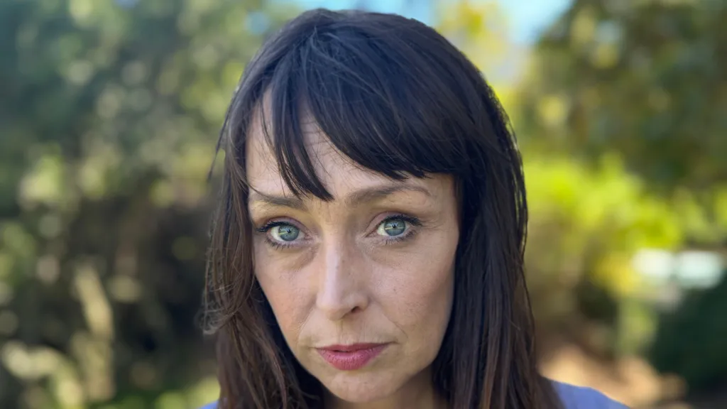 Juliette Bryant, now aged 43, has long brown hair with a fringe and stands outside with a serious expression 