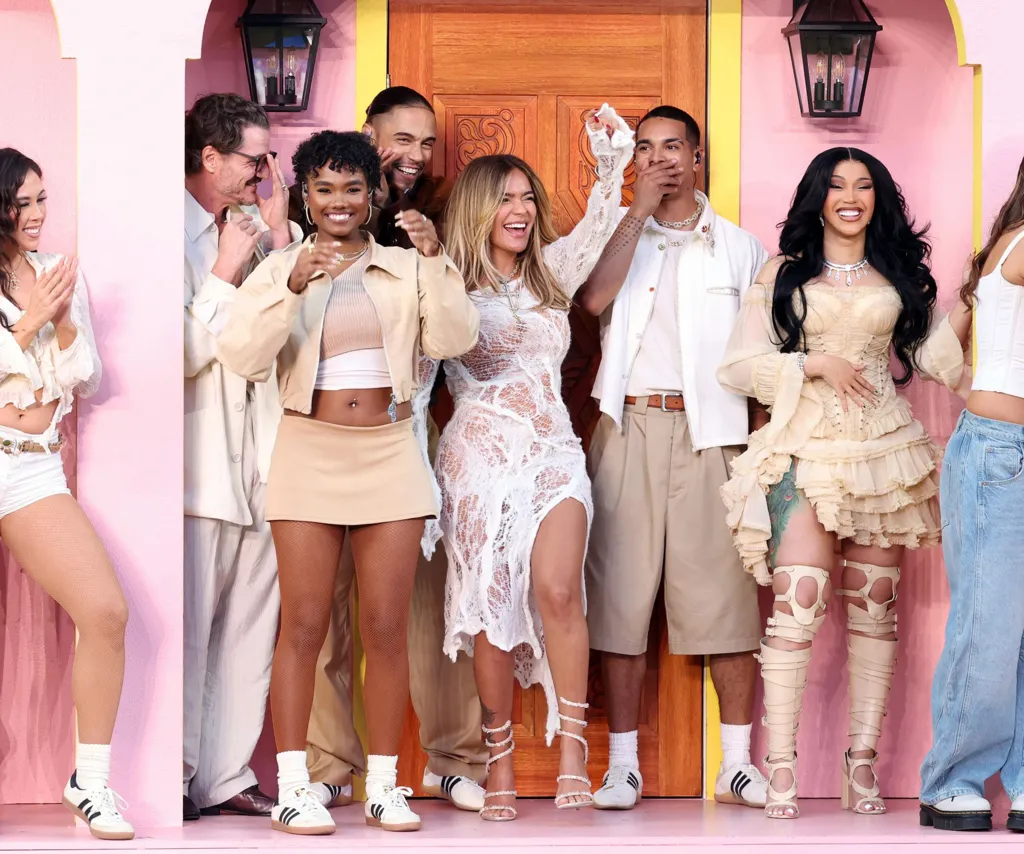 Karol G (centre) and Cardi B (right) among other people on stage smiling and dancing during the show.