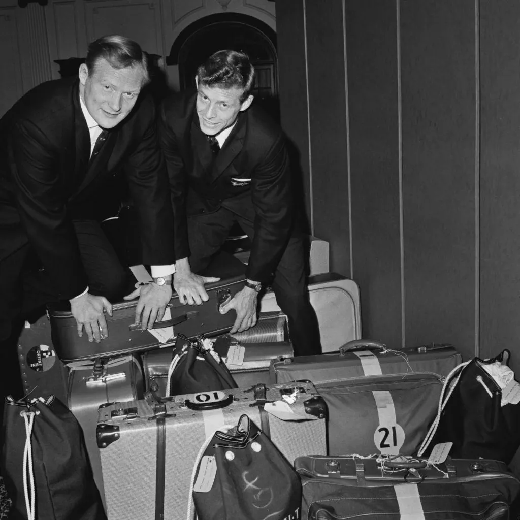 Black and white image of Arthur Smith and another rugby player in suits with a set of suitcases as they embark on a British and Irish Lions tour