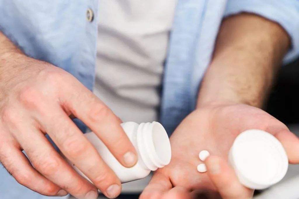 A man puts pills into his hand 