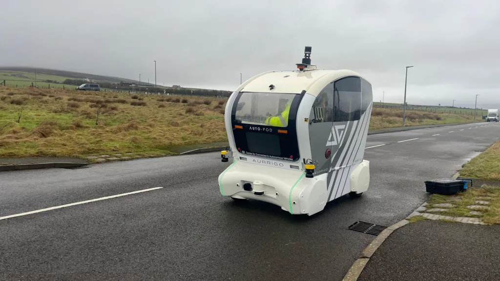 A white vehicle on a road with a sliding door opened and orange lights on the front