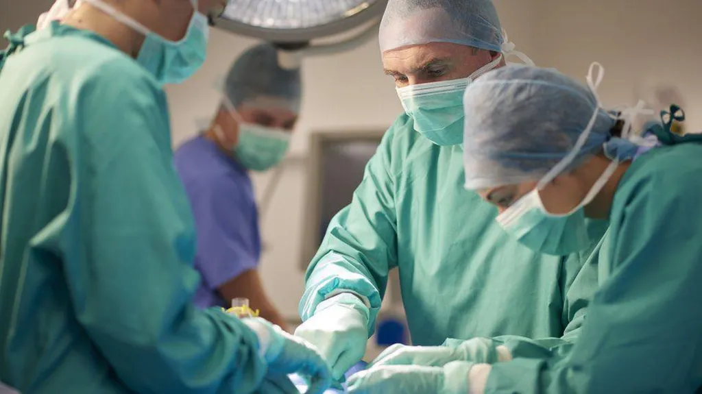 A group of surgeons operating on a patient in theatre