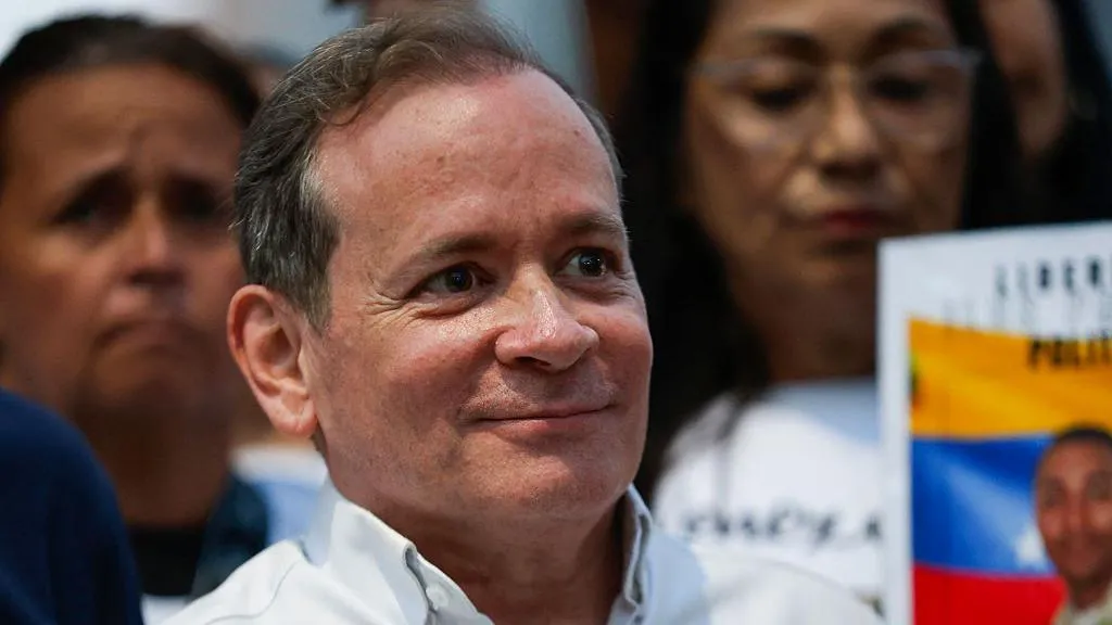 Juan Pablo Guanipa, who has greying hair and wears a white shirt, smiles as he is pictured outside following his release from prison in Caracas 