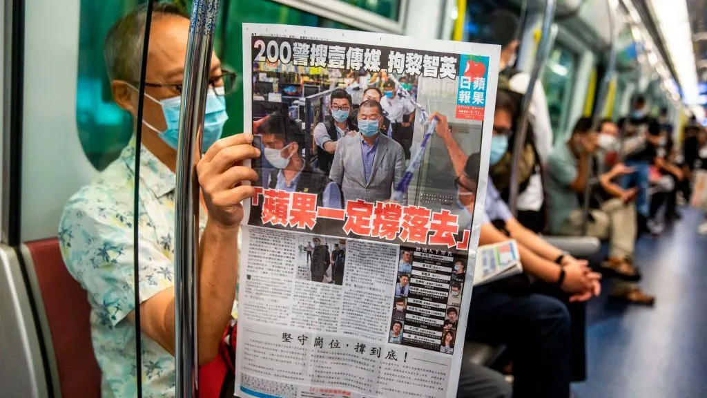 A man reads a copy of the now-defunct Apple Daily newspaper on a train in Hong Kong on 11 August, 2020, one day after authorities searched the newspaper's headquarters. "Apple will live on" reads the title of the page-one article. 