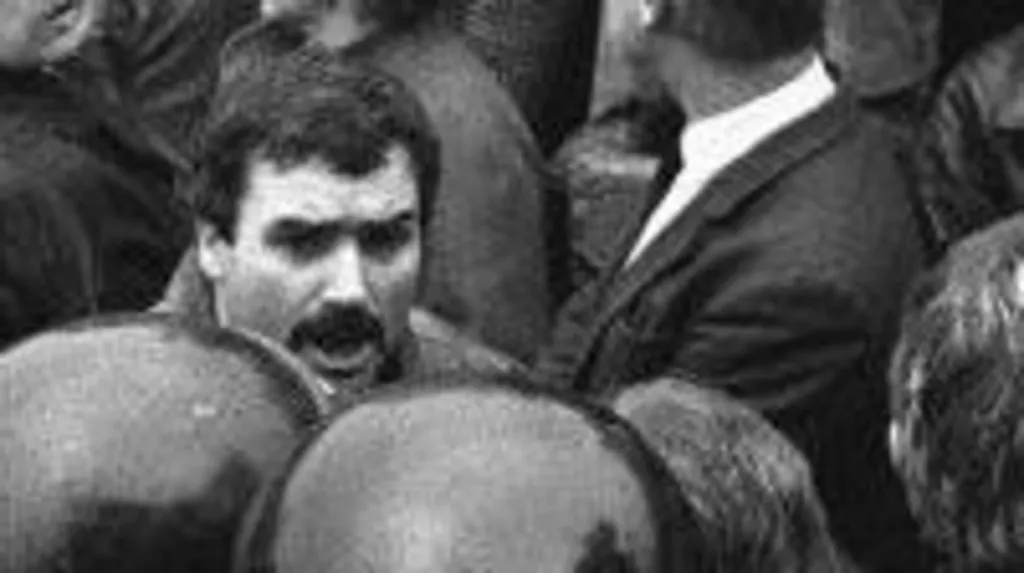 A black and white photograph of a Freddie Scappaticci in a crowd during an IRA funeral in the 1980s.  He has black hair and a thick black moustache.
