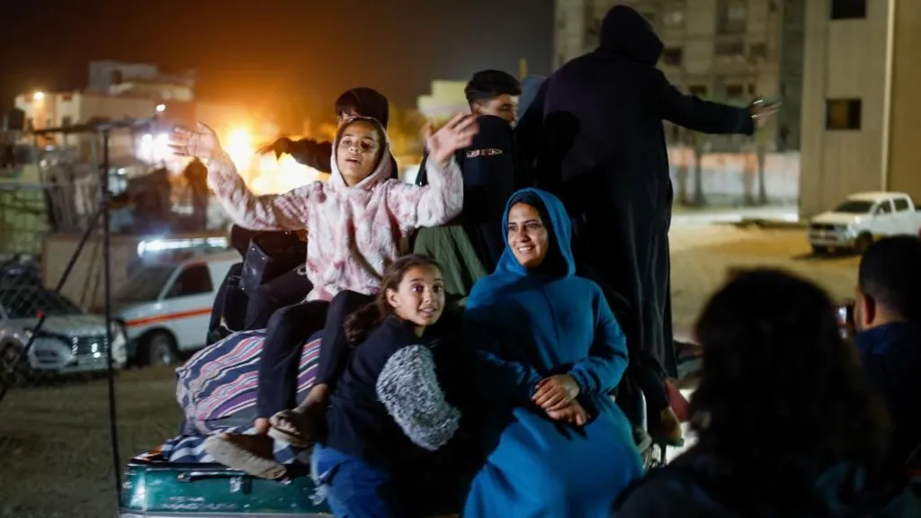 A woman and children, looking happy, sitting in the back of a pick-up truck at night-time after arriving in Gaza from Egypt