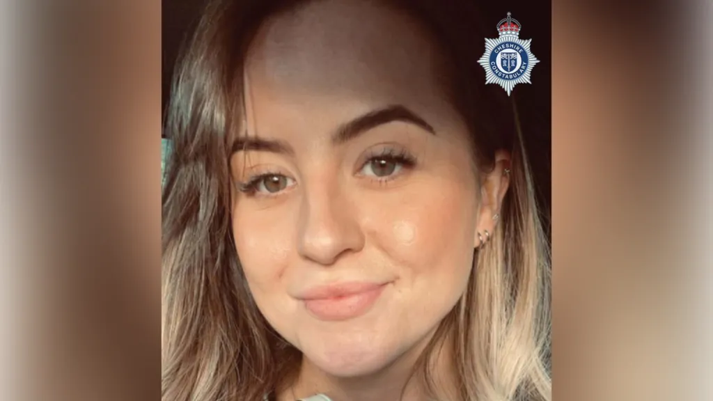A woman with long, light brown hair smiles as she takes a selfie.
