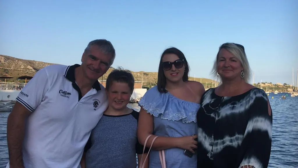 A family holiday photo - both parents and two children smiling 