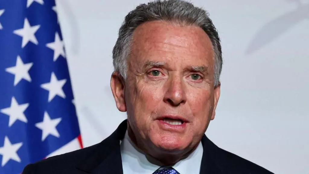 An image of the US Special Envoy to the Middle East, Steve Witkoff, speaking in front of the American Flag visible to the left.