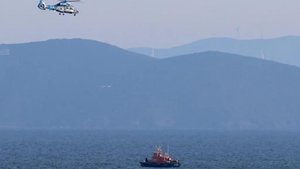 A Hellenic coastguard boat patrols the Greek waters as a helicopter flies overhead.