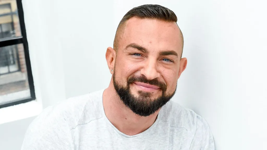 Robin Windsor in a grey T-shirt leaning against a white wall