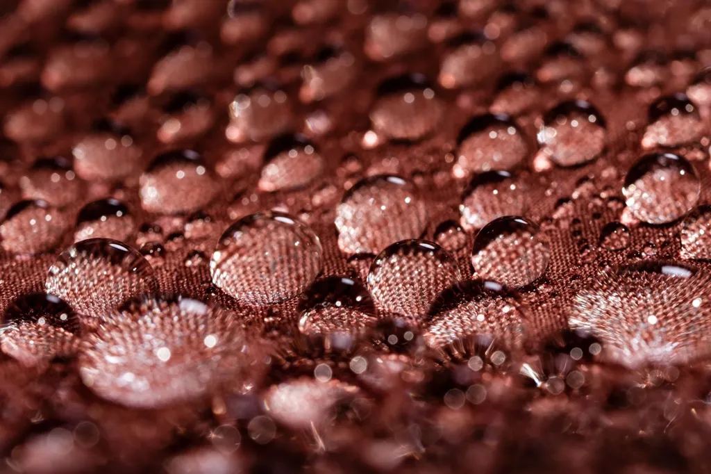 Water droplets gather on a piece of brown/pink material