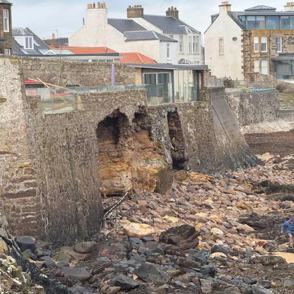 Brickwork on the sand and a broken wall underneath a house in Fife.