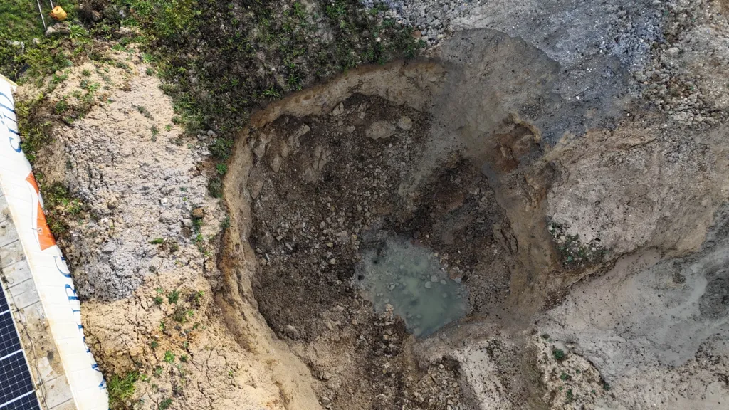 Aerial view shows a large empty pit with loose soil and stones