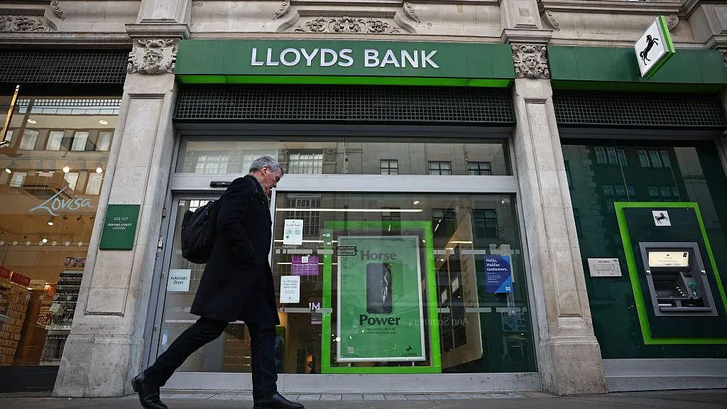 Man walk in front of a Lloyds Bank branch.