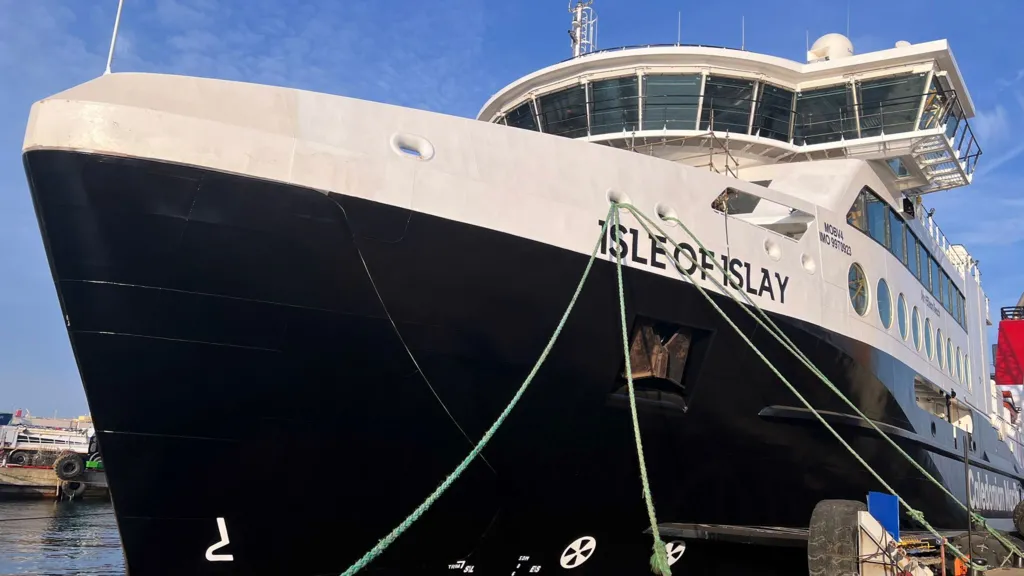 A black and white ship with Isle of Islay written on the side, moored by a quayside