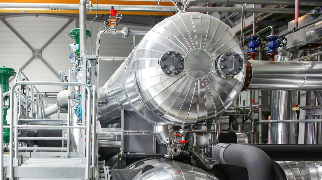 A large, shiny chrome tank with shiny pipework around it. 