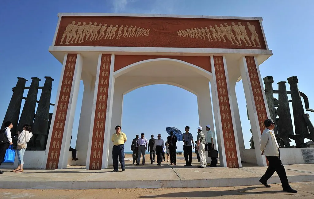 People stand under and around the door of no return