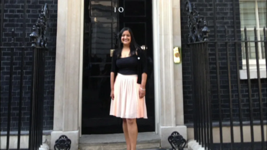 Sanju Pal, wearing a black top and a light coloured skirt, standing on the steps of the Prime Minister's residence in Downing Street.